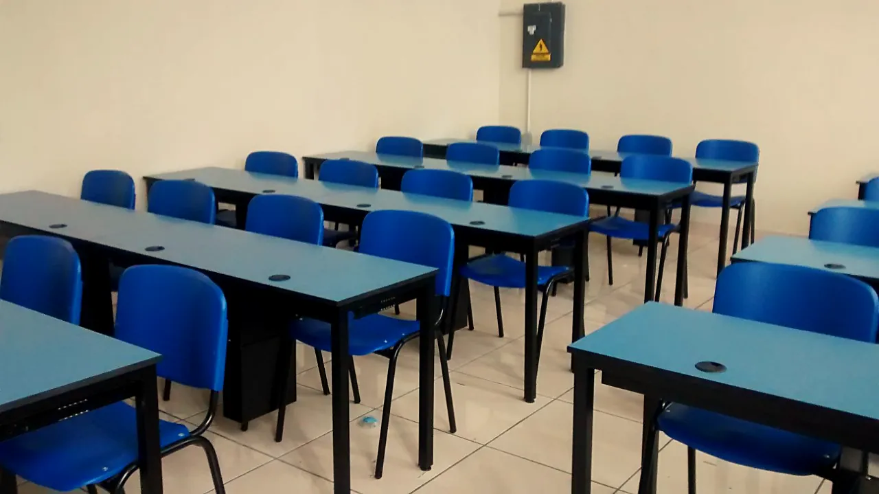 Aula con mesas azules y sillas en filas